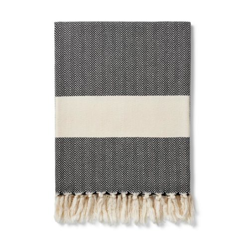 The Ferah organic cotton towel is a classic herringbone weave peshtemal with ecru block stripe & hand knotted tassels. Use it as a lightweight and quick drying towel, scarf, throw or sarong! 100 x 180 cm Seen here in ink black