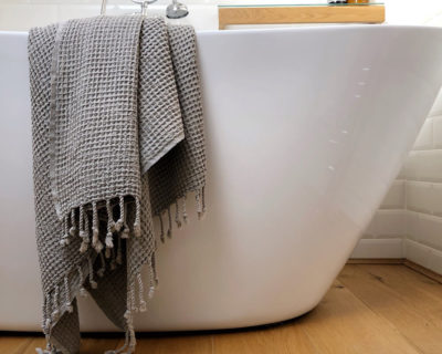 Rulo waffle weave towel in Lichen draped over the bath.