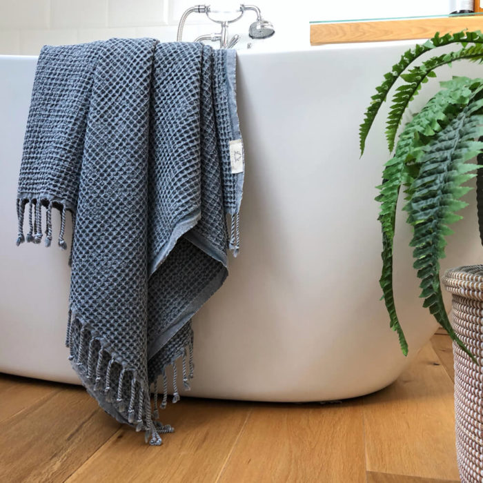 Rulo peshtemal draped over the bath. Traditionally woven in Turkey using eco conscious cotton. This colour is Marine blue.