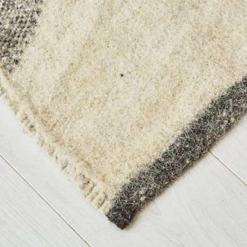 Jannu Radhi monochrome rug - sheeps wool Hand woven in Nepal on traditional back-strap looms, using un-dyed local sheep’s wool, this geometric monochrome rug is then washed in hot water to felt the wool. The result is a fair trade thick, hard wearing and washable monochrome rug, perfect for a neutral home decor with a natural style. High quality anti-slip fleece underlay also available in pre-cut sizes. Simply trim to fit. Small 166 x 144cm [65’” x 57”] Large 175 x 225cm [88” x 69”] Washable Pure Himalayan Wool Handwoven, felted These sheeps wool rugs are made by Radhi Weavers. Based on traditional radhi produced for the local market in Nepal, these monochrome rugs are often used as blankets, floor coverings and even worn to keep out the cold and rain. They're woven in the Himalayas by artisans using wool from local sheep, which is hand-spun. Stitch & Stitch use only the un-dyed wool in their eco-friendly washable rug designs - creamy white and a dark grey wool from black sheep. The radhi woolen rugs are first woven on simple back-strap looms, which can be set up anywhere - against a tree or a building. The looms are narrow, and the cloth woven on them is only about 36cm wide. To create a larger piece such as a carpet, several strips of cloth are sewn together by hand.