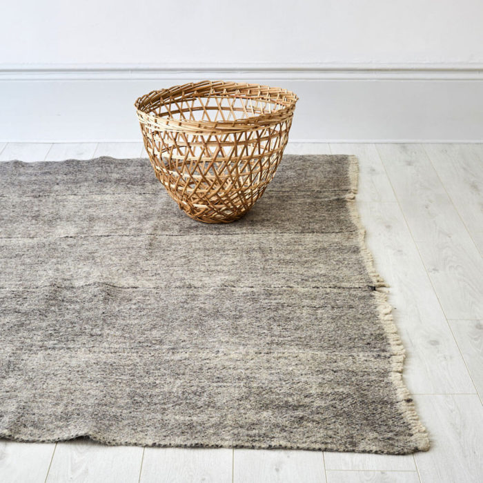 Himalayan grey wool rug. Hand woven in Nepal on traditional back-strap looms. Using un-dyed local sheep’s wool, these boiled sheeps wool rugs are then washed in hot water to felt the wool. The result is a thick, hard wearing and washable monochrome grey wool rug, perfect for a neutral, natural home. Anti-slip underlay also available in pre-cut sizes. Simply trim to fit on installation. Small 166 x 144cm [65’” x 57”] Large 175 x 225cm [88” x 69”]. Washable, Pure Himalayan Wool. Handwoven, felted. These sheeps wool rugs are made by Radhi Weavers. Based on traditional radhi produced for the local market in Nepal, these best selling rugs are often used as blankets, floor coverings and even worn to keep out the cold and rain. They're woven in the Himalayas by artisans using wool from local sheep, which is hand-spun. Stitch & Stitch use only the un-dyed wool in their fair trade rug designs - creamy white and a dark grey wool from black sheep. The radhi are first woven on simple back-strap looms, which can be set up anywhere - against a tree or a building. The looms are narrow, and the cloth woven on them is only about 36cm wide. To create a larger piece such as a carpet, several strips of cloth are sewn together by hand.