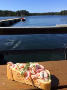 Seafood lunch of prawns on crusty bread, served on a jetty overlooking the islands of Småland's archipelago.