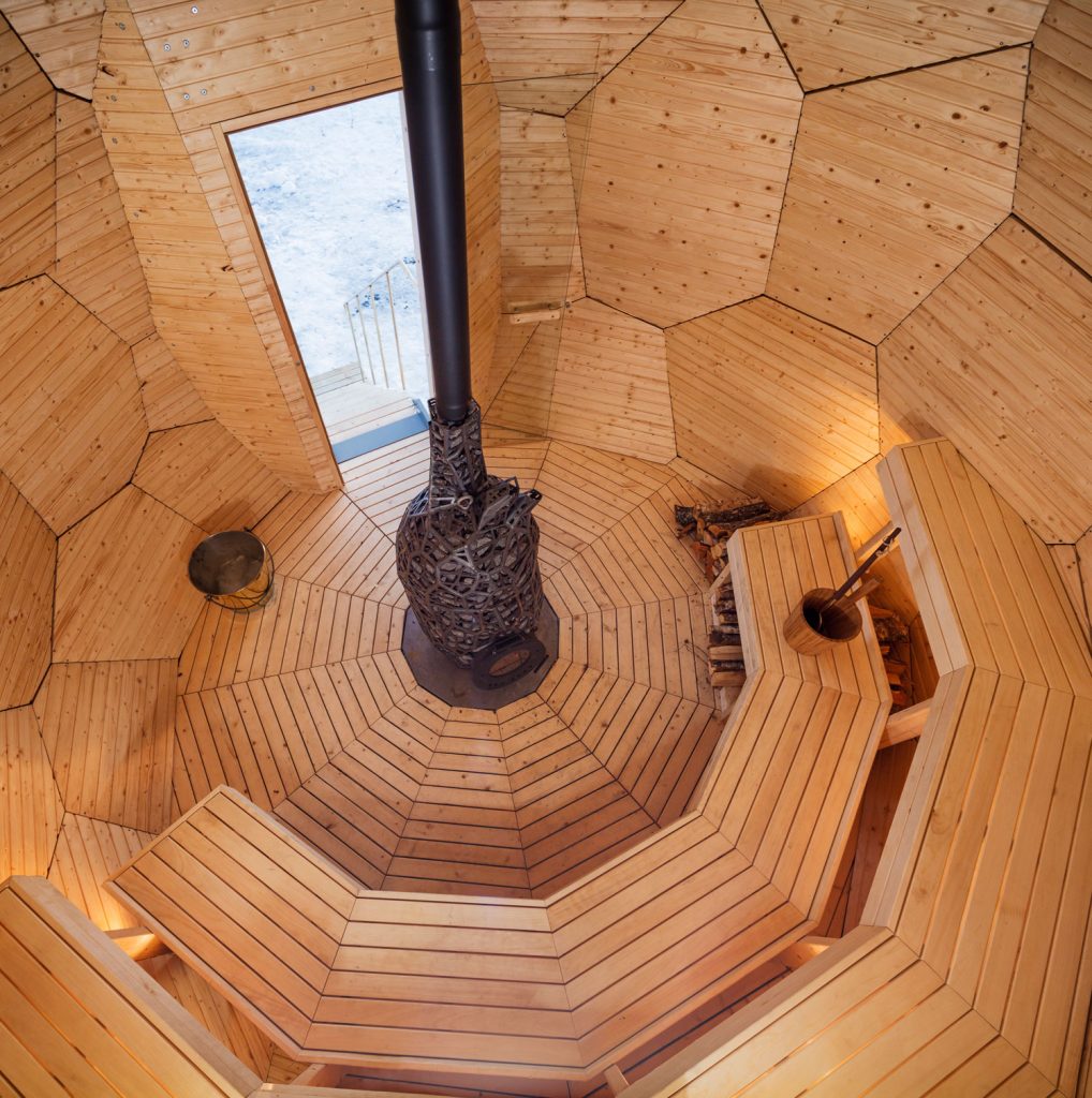 The dome shaped interior of this outdoor sauna is warm wood. The curved bench seats 8.