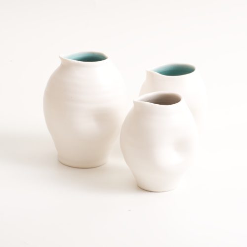 Handmade dimpled porcelain jug set. With a matt white glaze on the outside and soft coloured inside. Available in white, grey and turquoise, in two sizes. Perfectly formed dimples to fit in your hand. Handmade by Linda Bloomfield in London. Sold on chalkandmoss.com.