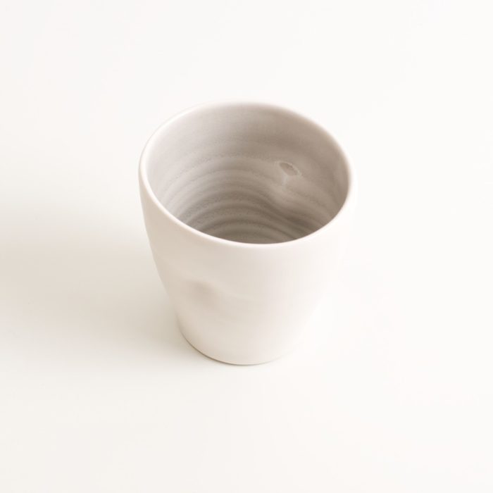 Handmade Dimpled Cup grey glaze. With a matt white glaze on the outside and soft coloured inside. Available in pale blue, pale pink, grey and turquoise. Perfectly formed dimples to fit in your hands. Hand thrown by Linda Bloomfield in her West London studio. Sold on chalkandmoss.com.