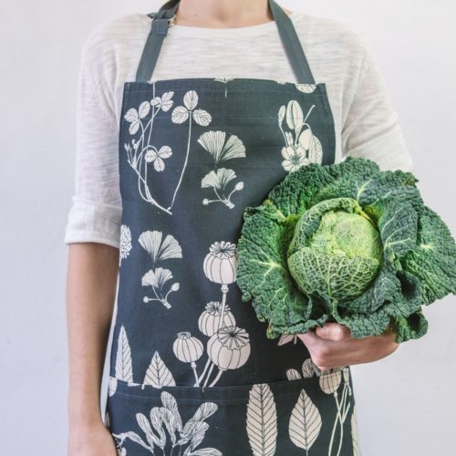 Botanical apron made from undyed cotton, and using water based dyes in the screen print. Available in several colours, seen here in charcoal. By Softer + Wild, available on nature connected homeware shop Chalk & Moss.