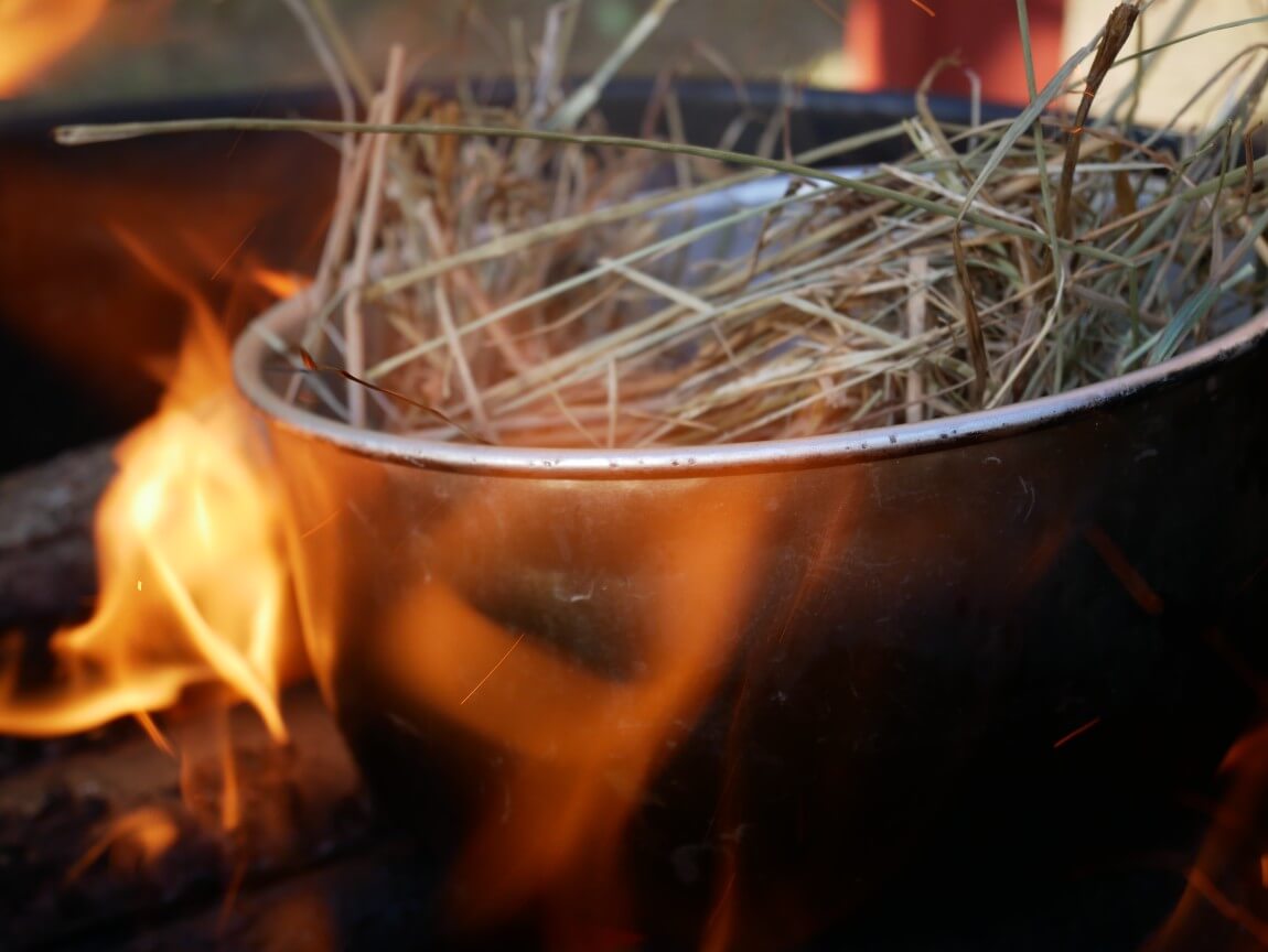 Char the hay / straw in a pan over the open fire (the pan will go black on the outside, so don't use grandma's best). It will catch fire and turn to char dust. Then mix with sea salt and grind, and use as seasoning.