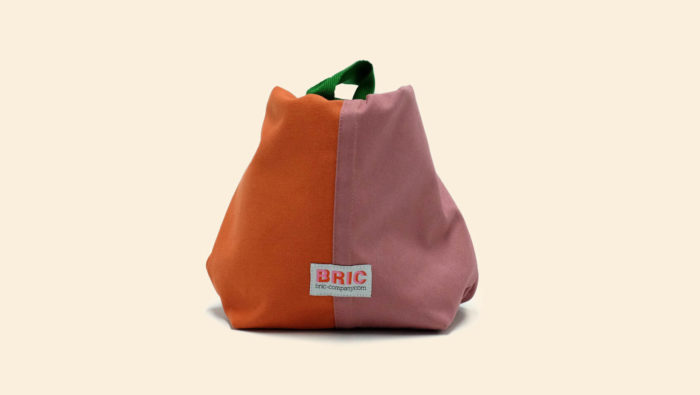 Bric Classic environmentally friendly cotton lunch bag with BPA free removable waterproof lining, perfect for cold food and hot leftovers. Rolls down to form a picnic bowl. Comes in several colours. Dimensions: H 25cm W 30cm Width at bottom 14cm, depth at bottom 9cm Optional spare washable lining. Seen here in orange and pink, tied.