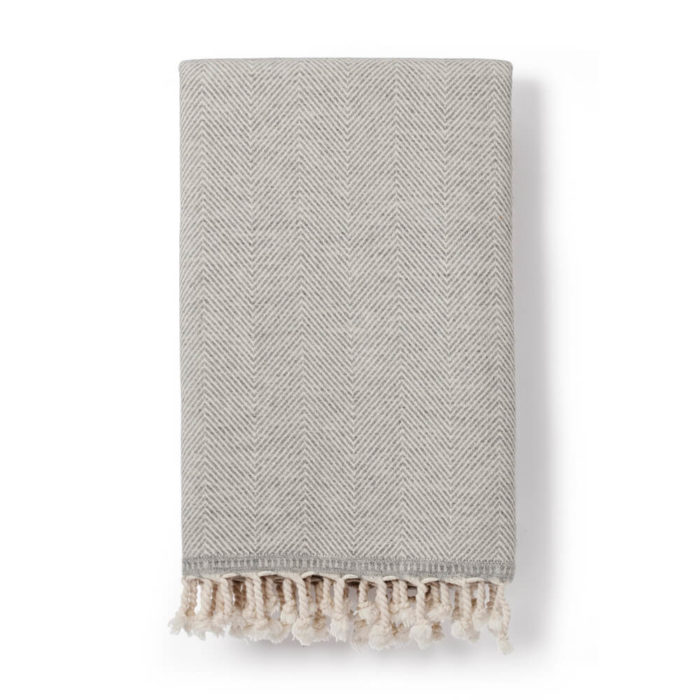 Wool throw made from an organic cotton and lambs wool blend, with a classic herringbone pattern. This makes it both warm and soft on the skin. 130 x 185cm. Seen here in grey (also available in denim blue).